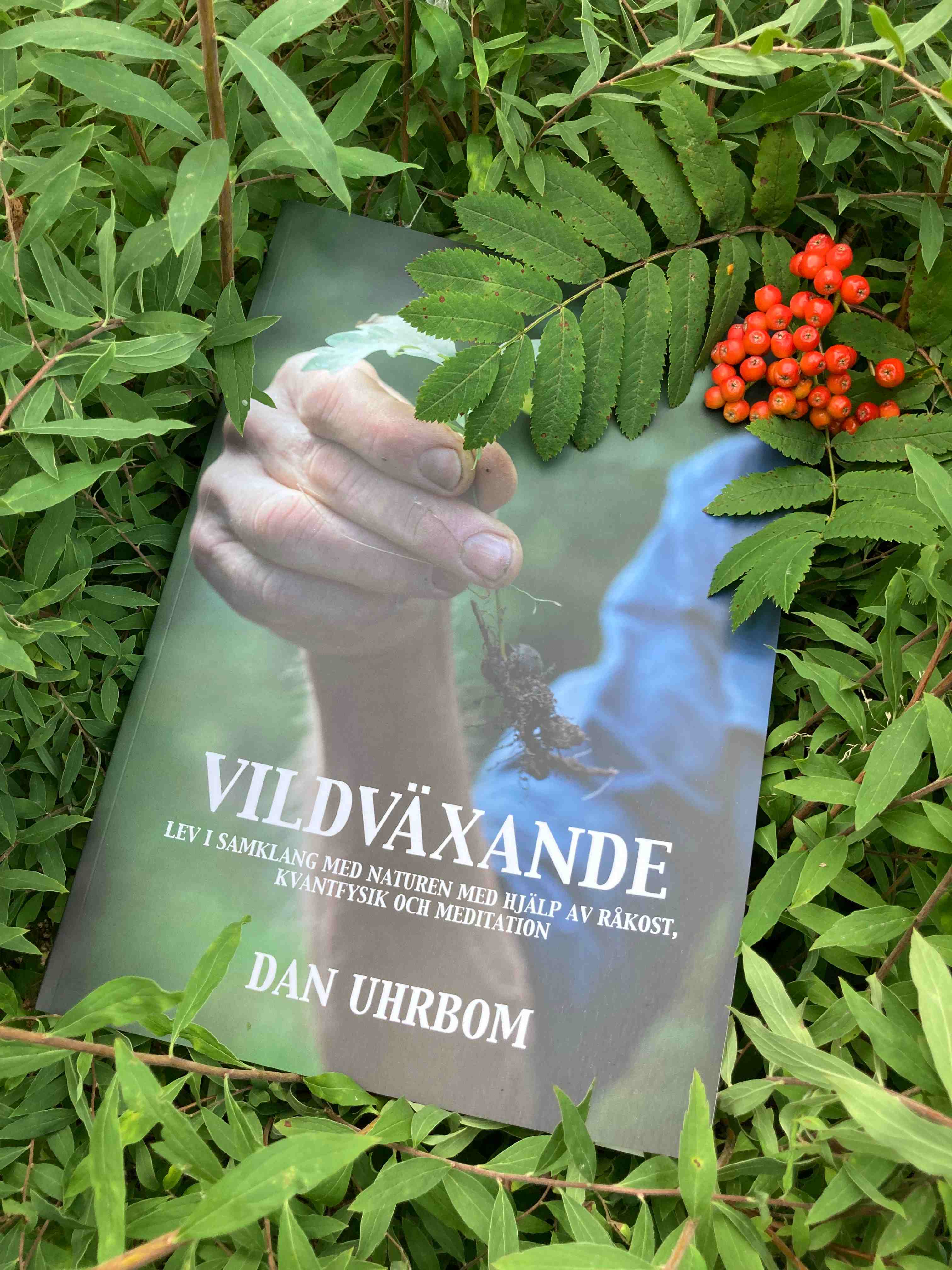 Omslag till boken Vildväxande av Dan Uhrbom omgiven av gröna blad